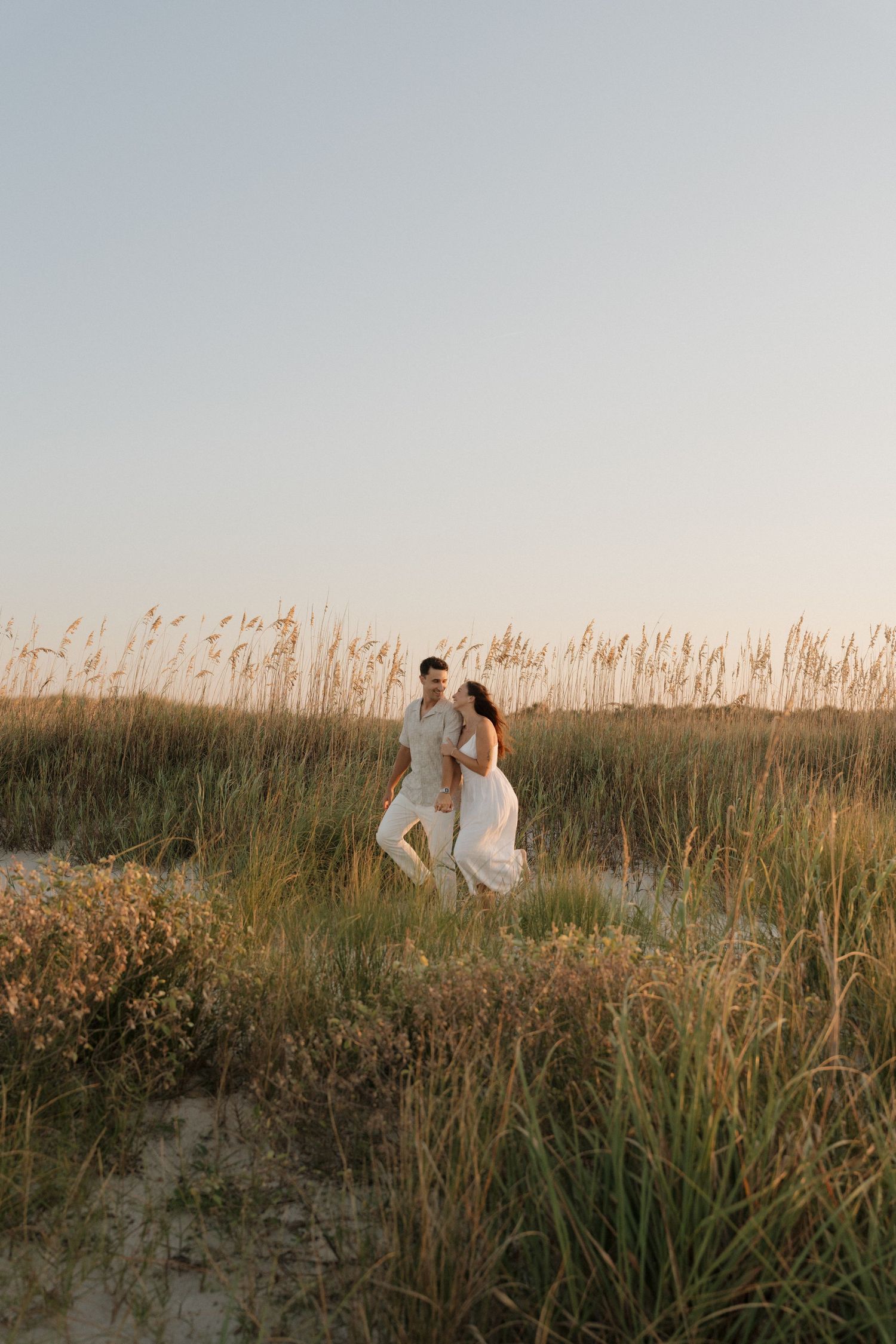 Couple shares tender moment by wooden fence during maternity photoshoot at sunset.