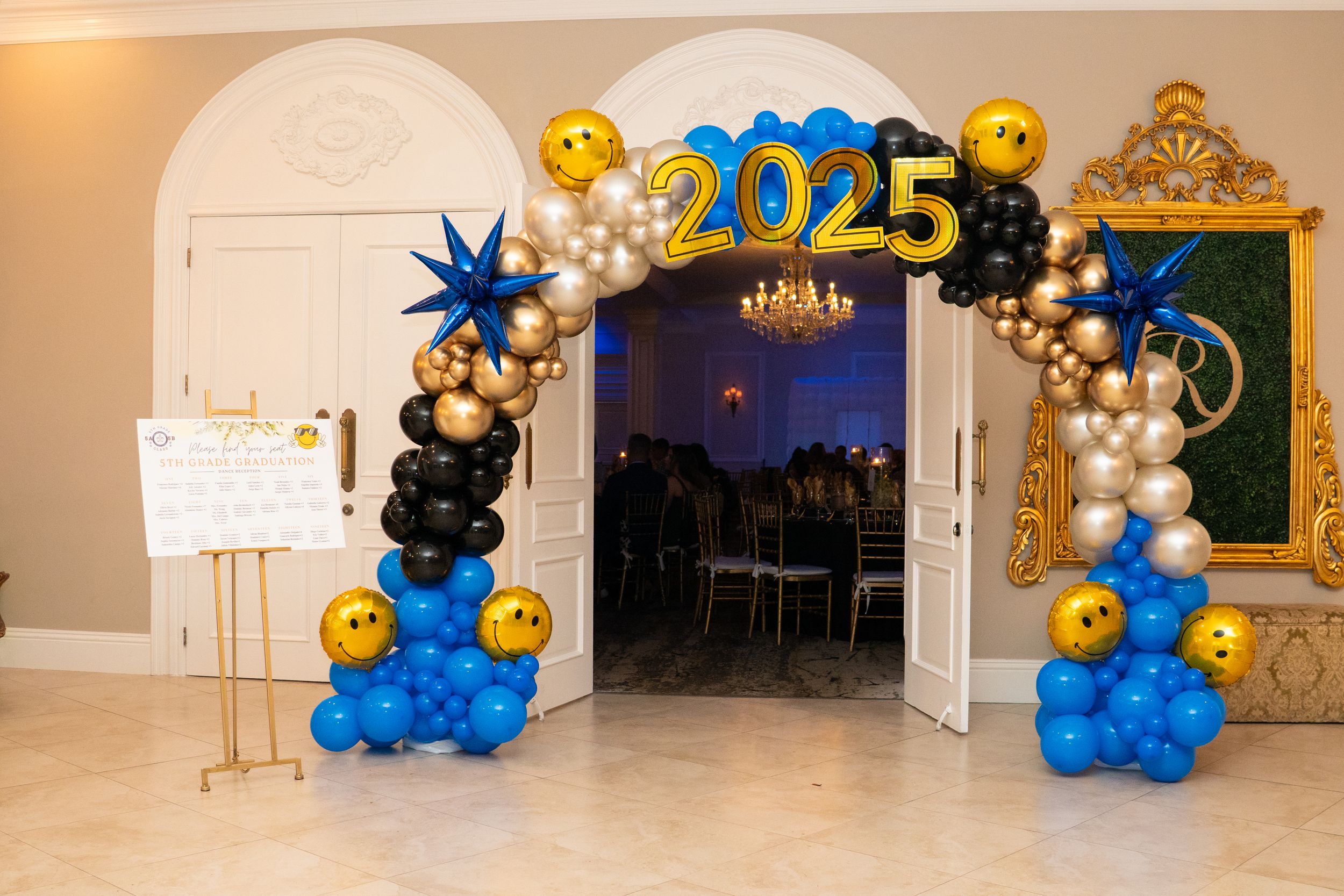 Elegant 2025 graduation party entrance with blue, gold, and black balloon arch decor.