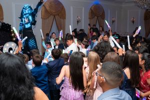 Crowd of children and adults celebrating at graduation party with glowing foam sticks.