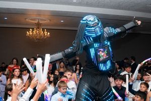 Performer in LED light-up robot costume entertaining crowd of children at graduation party.