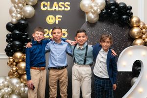 Four boys posing together in front of a Class of 2025 graduation balloon backdrop.
