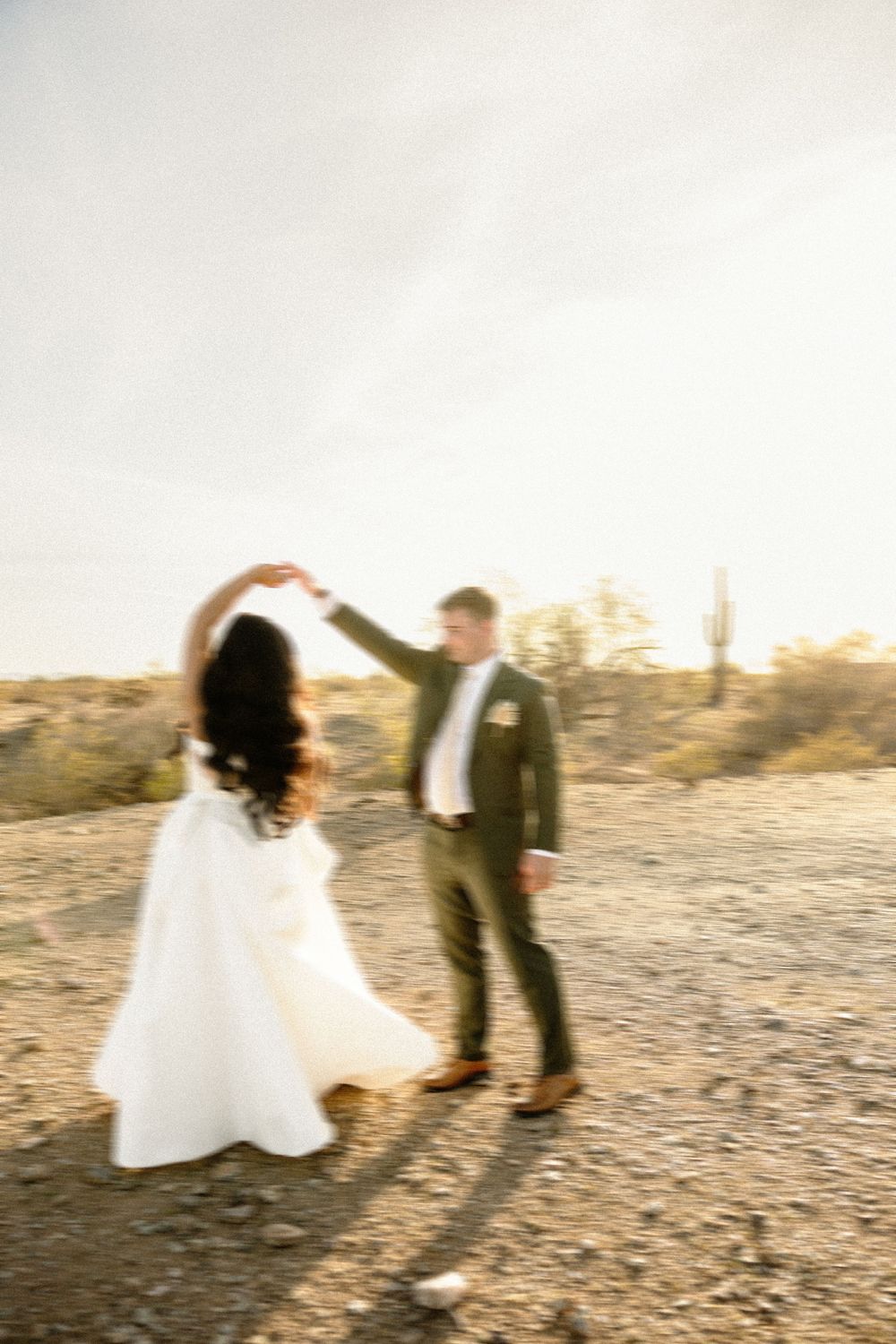 Artistic motion blur captures couple dancing in desert setting at sunset.