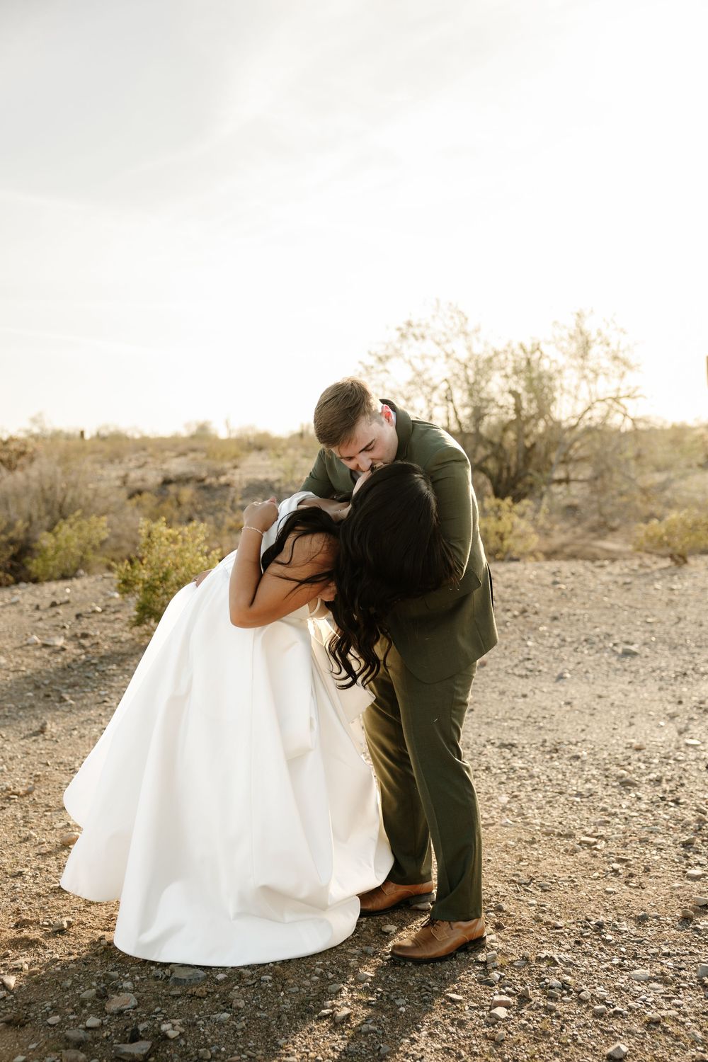 Romantic couple shares intimate dance poses against desert landscape at golden hour.