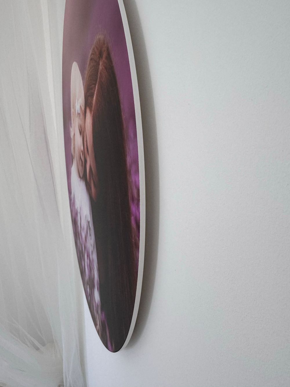 A round wall-mounted frame viewed from an angled side perspective against a white wall.
