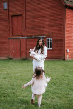 A heartwarming moment between family members playing on grass in front of a rustic red barn.