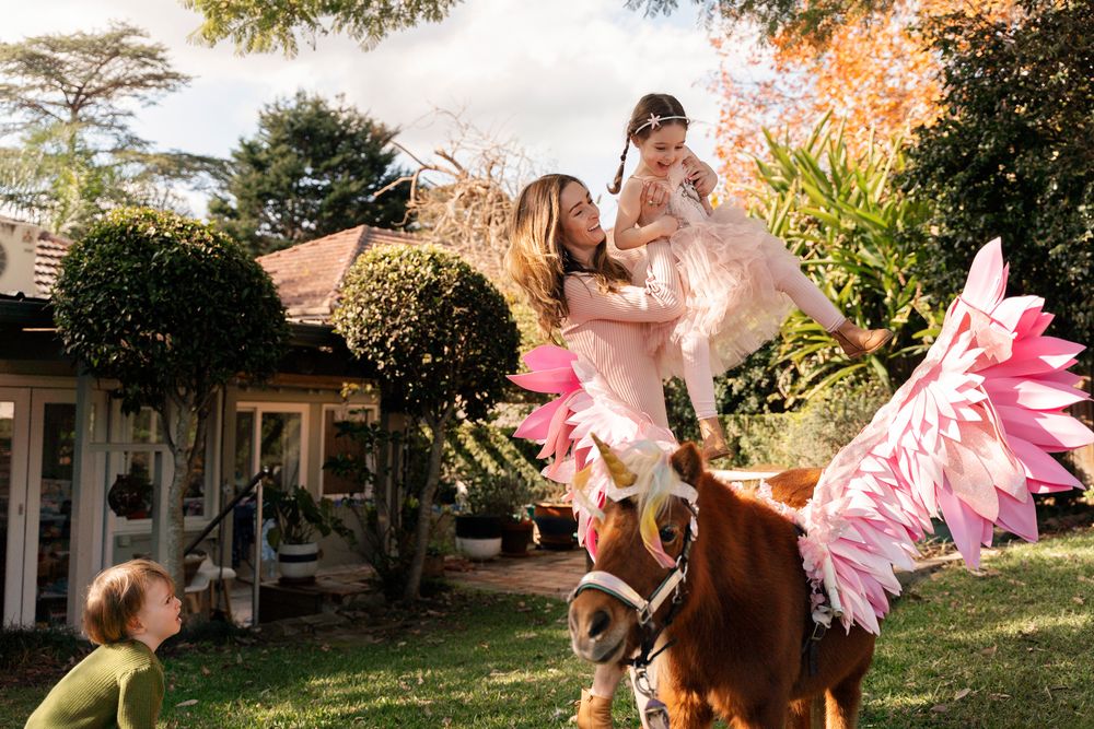 Mom is putting on her daughter on a unicorn during a unicorn photoshoot in Sydney Lane Cove