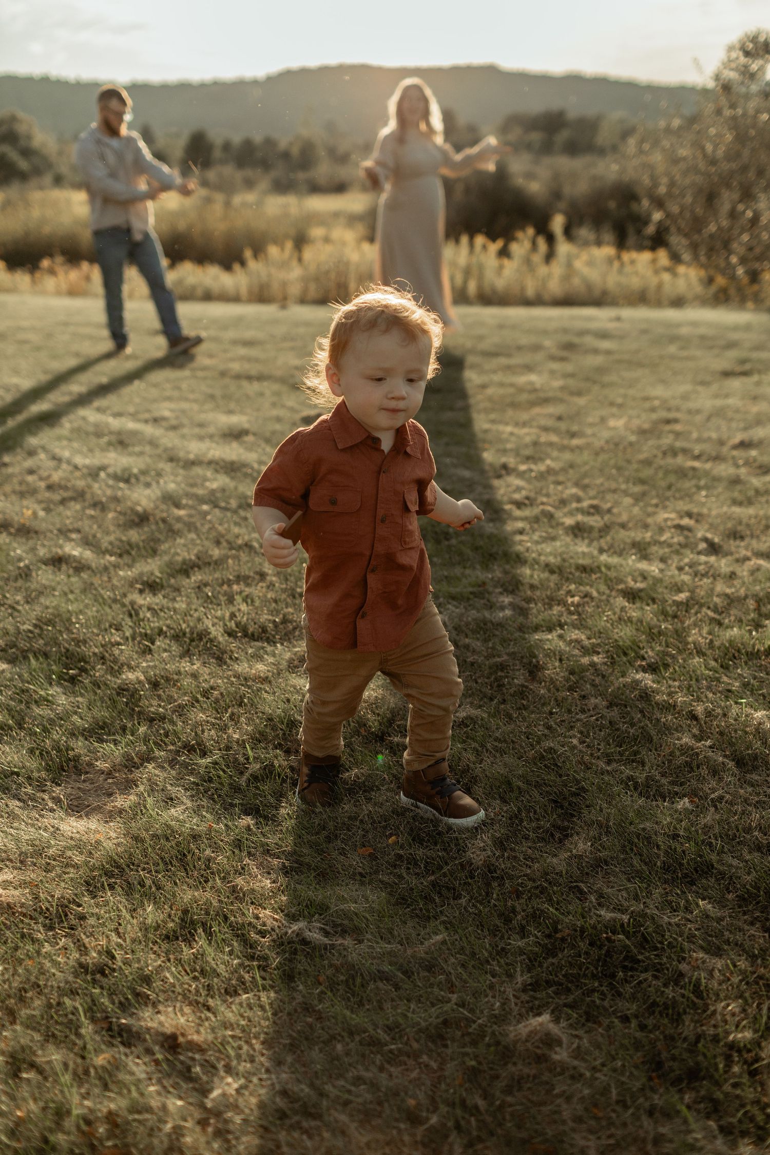 Child wearing a black t-shirt and cowboy hat laughs joyfully against a gray background.