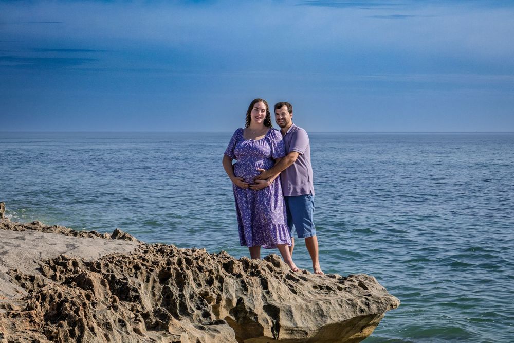 Couple enjoying a romantic moment together on a rocky beach overlook with ocean views.