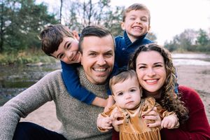Family cuddling together by a creek during an outdoor family photo session