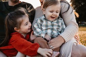 Candid sibling photo of a toddler sister tickling her baby brother’s foot