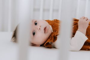 Intimate newborn portrait of a baby looking through crib bars