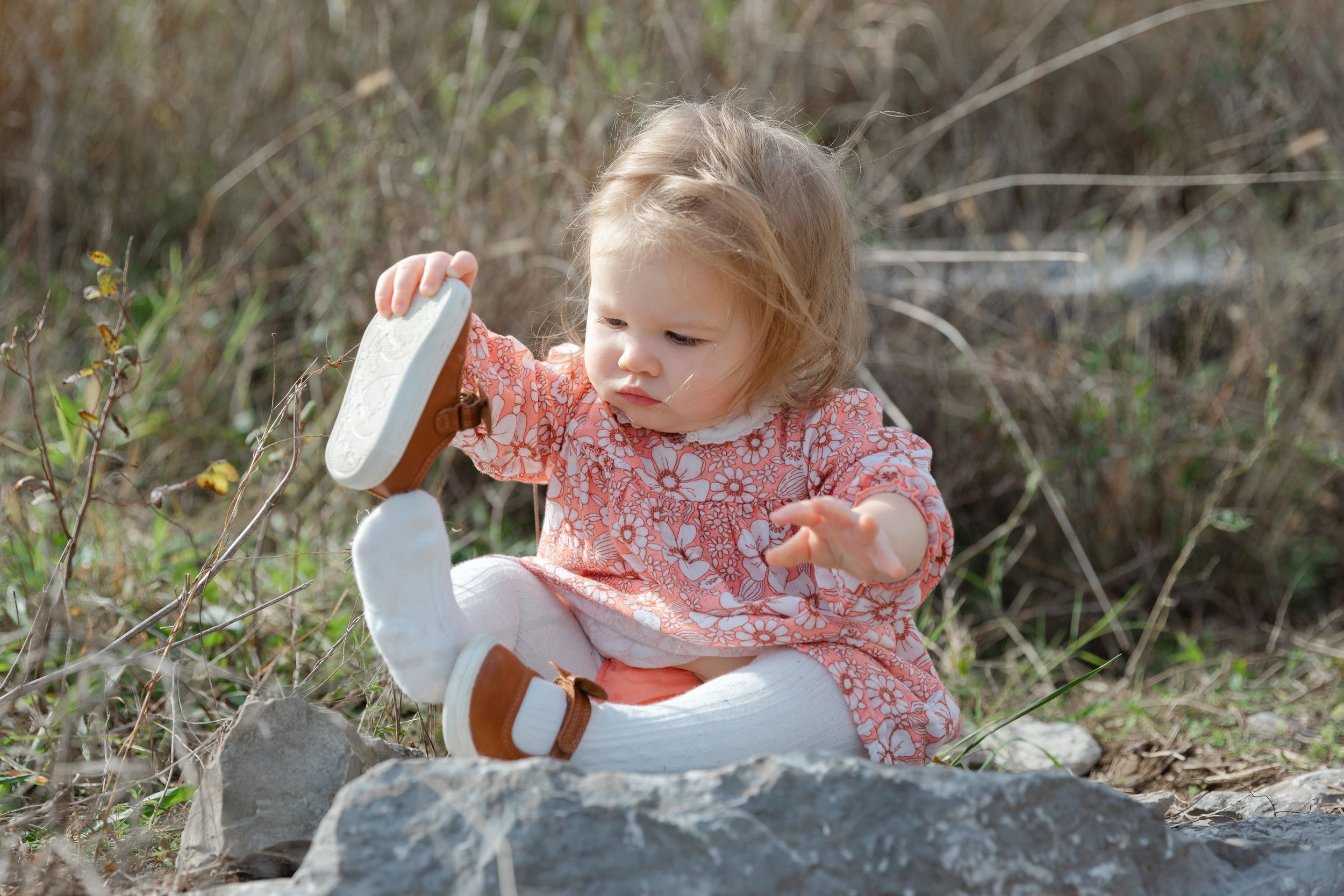 Candid lifestyle photo of a toddler putting a shoe back on