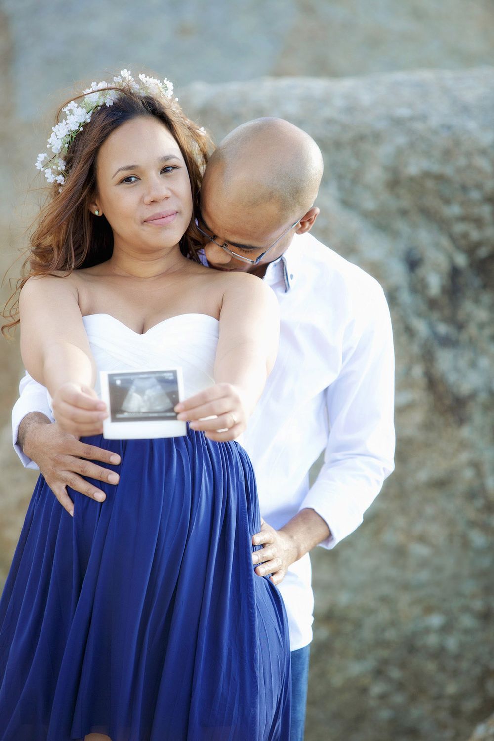 Mom showing ultrasound picture, dad kissing her, Melbourne maternity shoot.