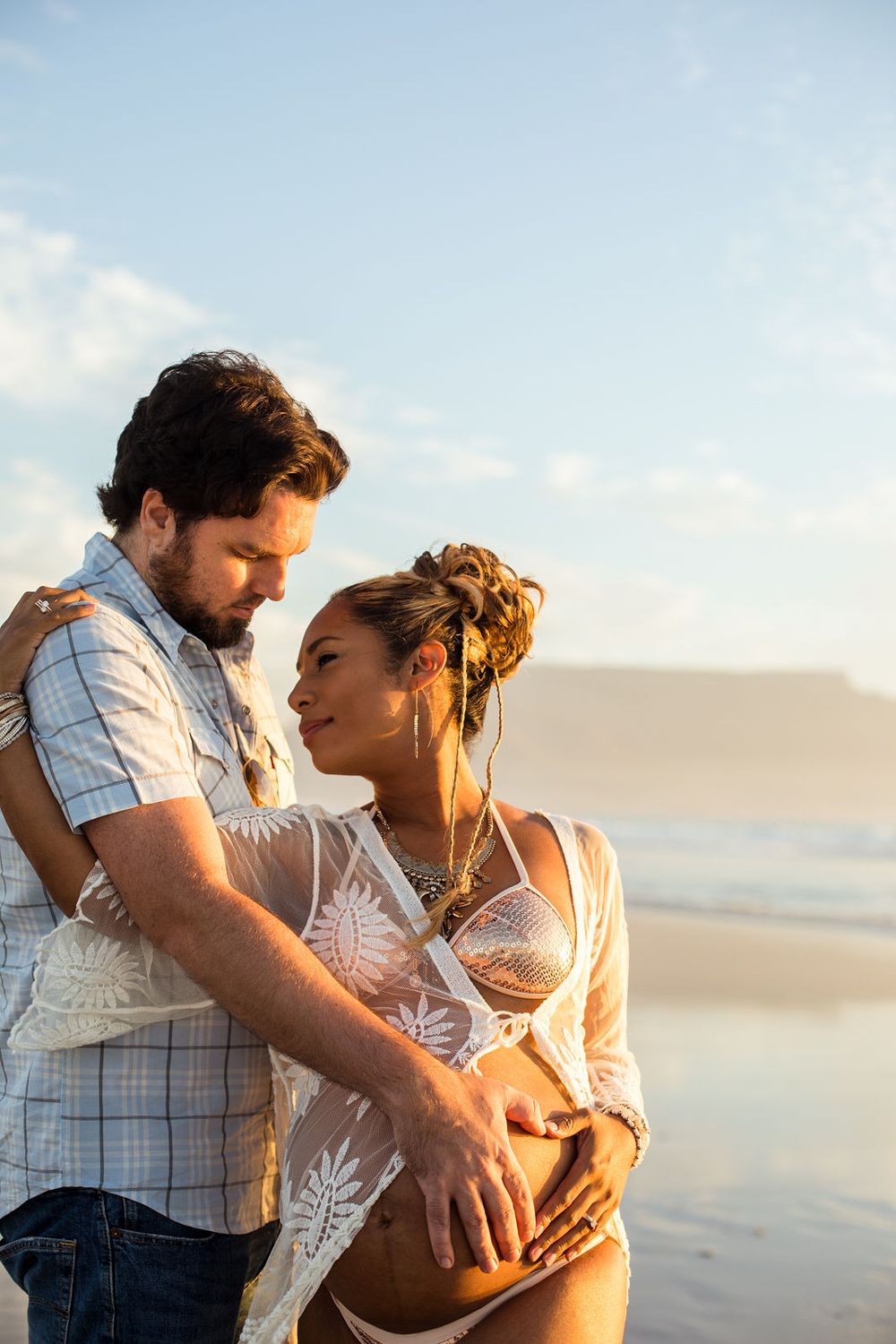 Parents-to-be holding making heart shape in a joyful Melbourne beach maternity shoot