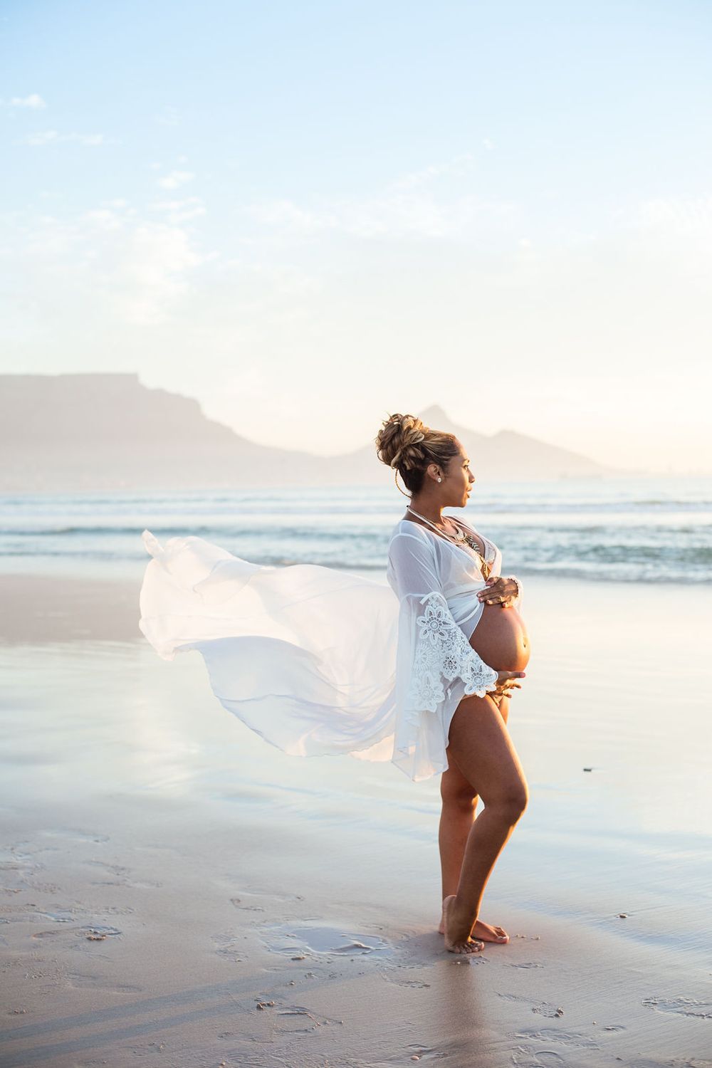 Young mom-to-be at Melbourne beach proudly showing her baby bump.
