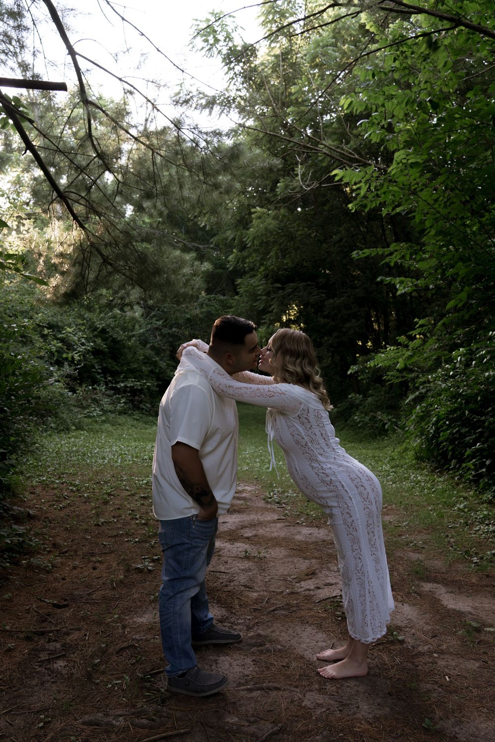 A couple dances together on a dirt path surrounded by green foliage.