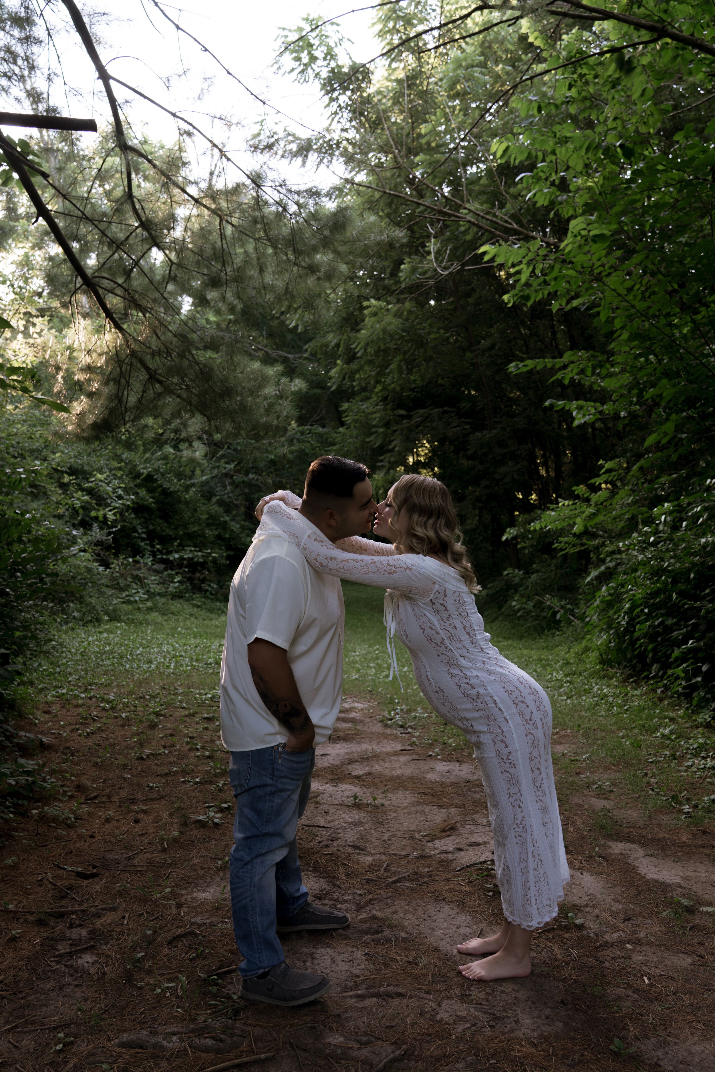 A couple dances together on a dirt path surrounded by green foliage.