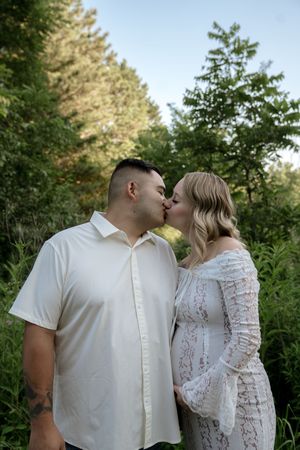 A romantic moment captured between a couple in white attire against a natural backdrop.