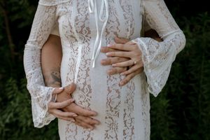 Close-up details of a white lace maternity dress with bell sleeves.