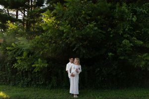 A romantic photoshoot of a couple in white attire surrounded by greenery.