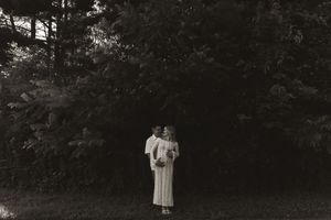 A couple shares an intimate embrace during an outdoor photo session at dusk.