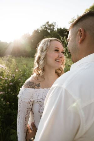A romantic sunset photoshoot in a wildflower field features a couple sharing a joyful moment together.