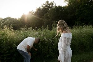 A couple shares a lighthearted moment in a meadow during their sunset photoshoot.