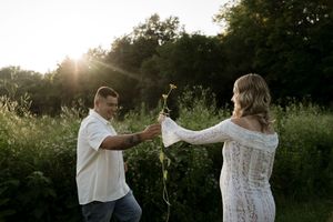 A couple exchanges flowers during their sunset photoshoot in a meadow.