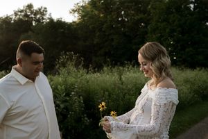 A couple shares a sweet moment while holding wildflowers during their outdoor photoshoot.