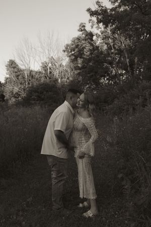 A couple embraces in a romantic outdoor photoshoot at sunset with trees in the background.