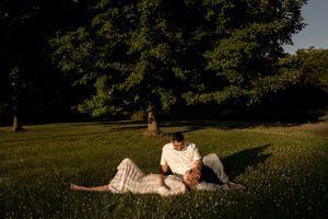 Couple poses together on grassy field during sunset maternity session.