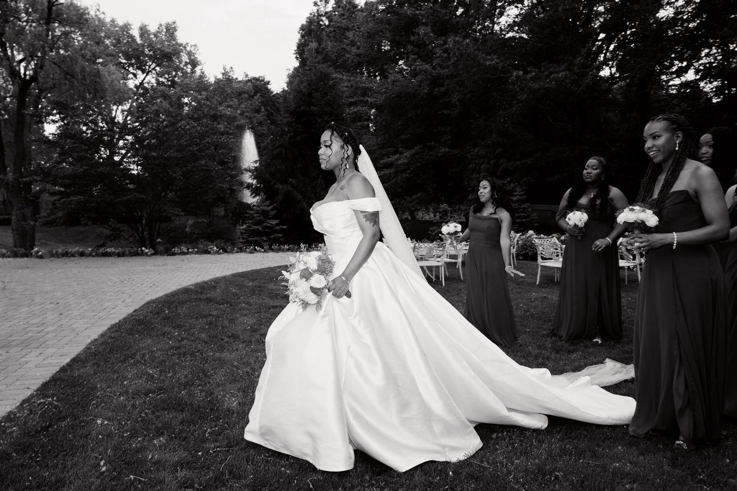 Black and white wedding photo series showing flowing dress train on grassy outdoor setting.