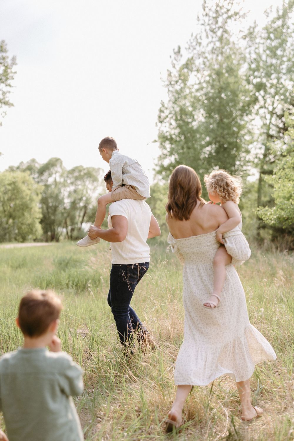 Candid wedding couple walking together in a sunny summer meadow with tall grass.