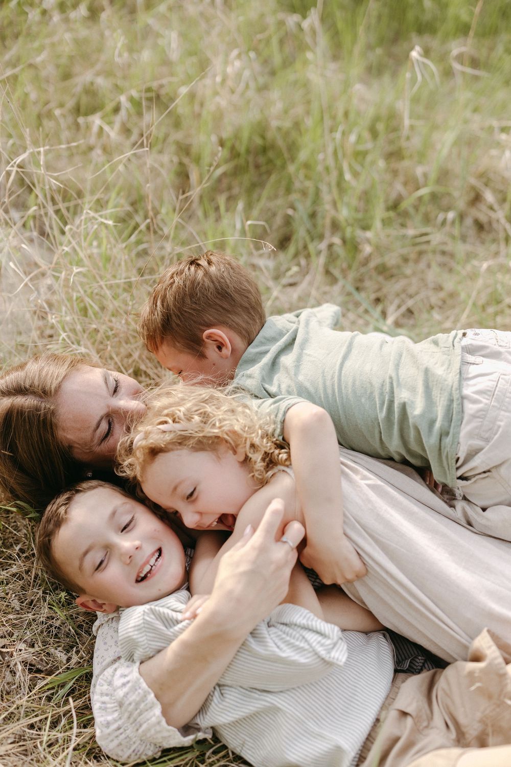People laying together on grassy ground sharing playful and affectionate moments.