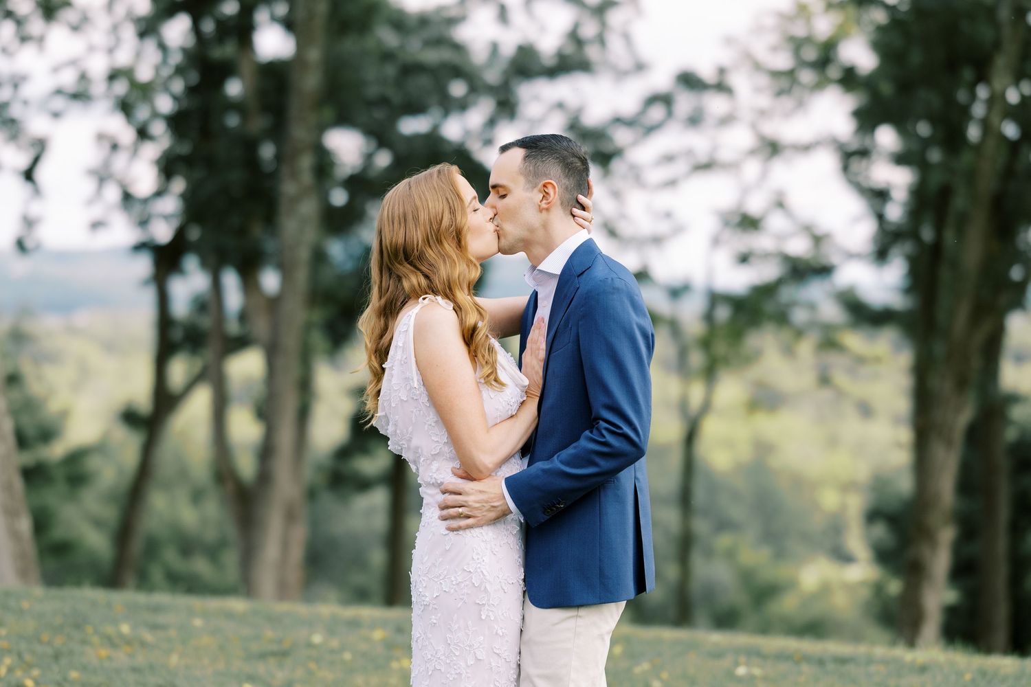 A couple in wedding attire embrace amongst tall trees during their outdoor forest ceremony and photo session at Pendry Natirar in Peapack.
