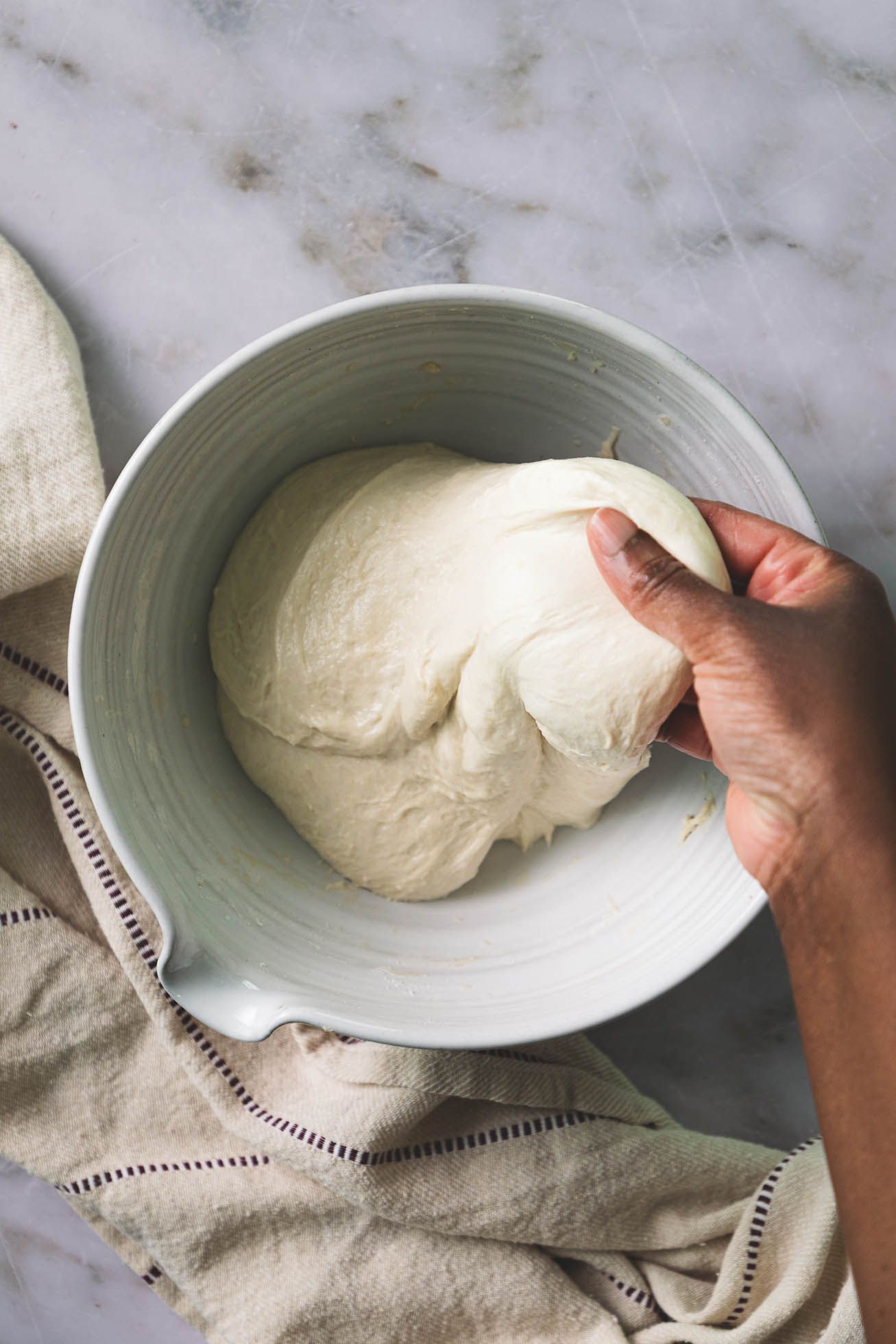 Step by step progression of hands placing and removing pizza dough from a light blue ceramic plate.