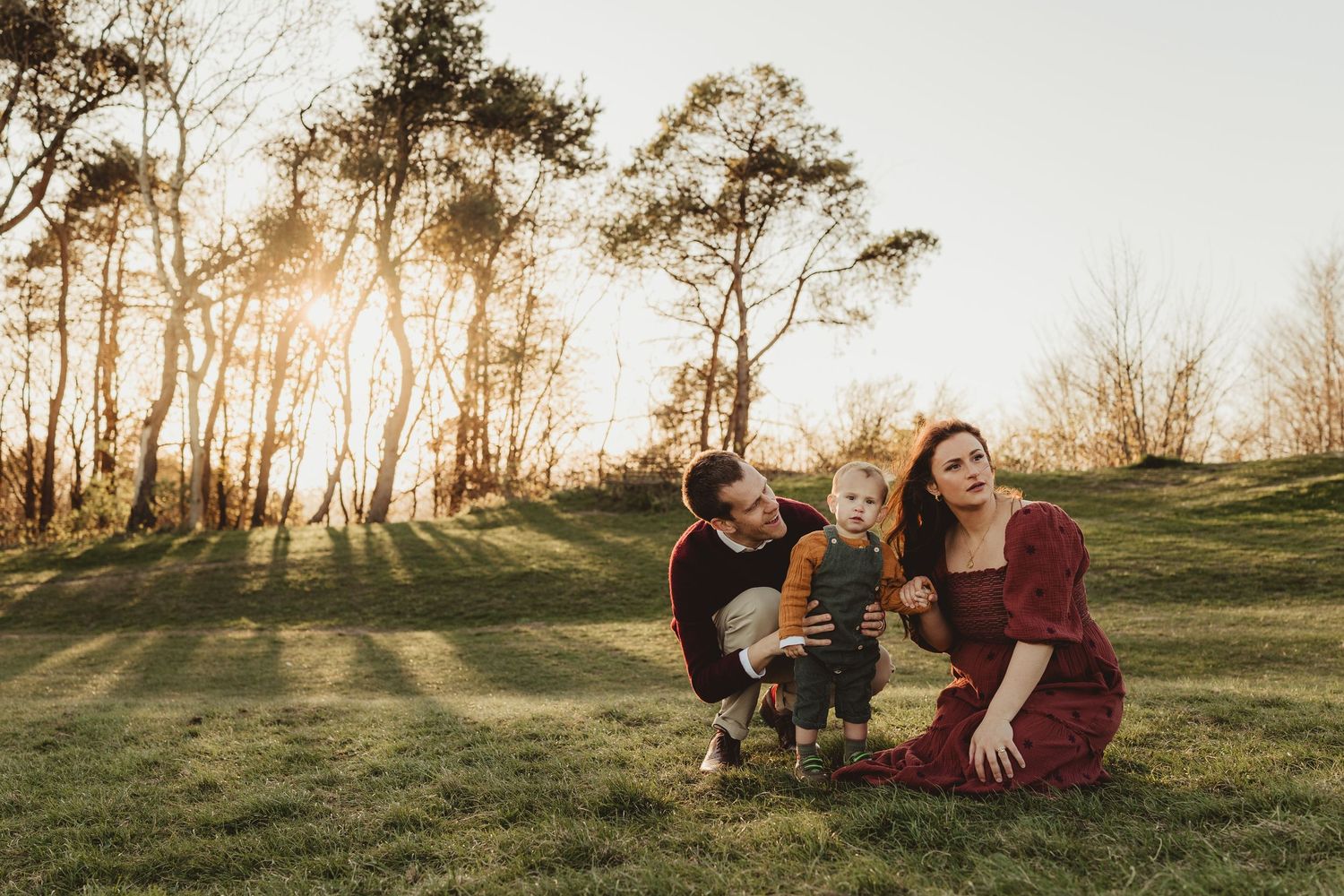 People enjoy a playful moment together in a golden field at sunset with wildflowers blooming around them.