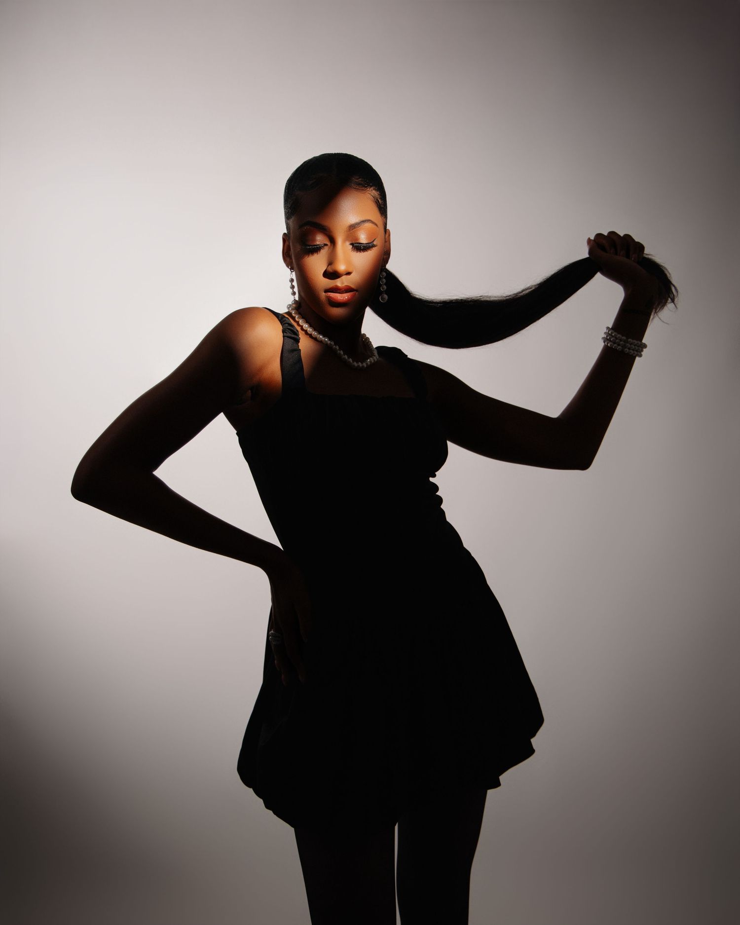 Artistic portrait of model in black dress posing with long braided hair.