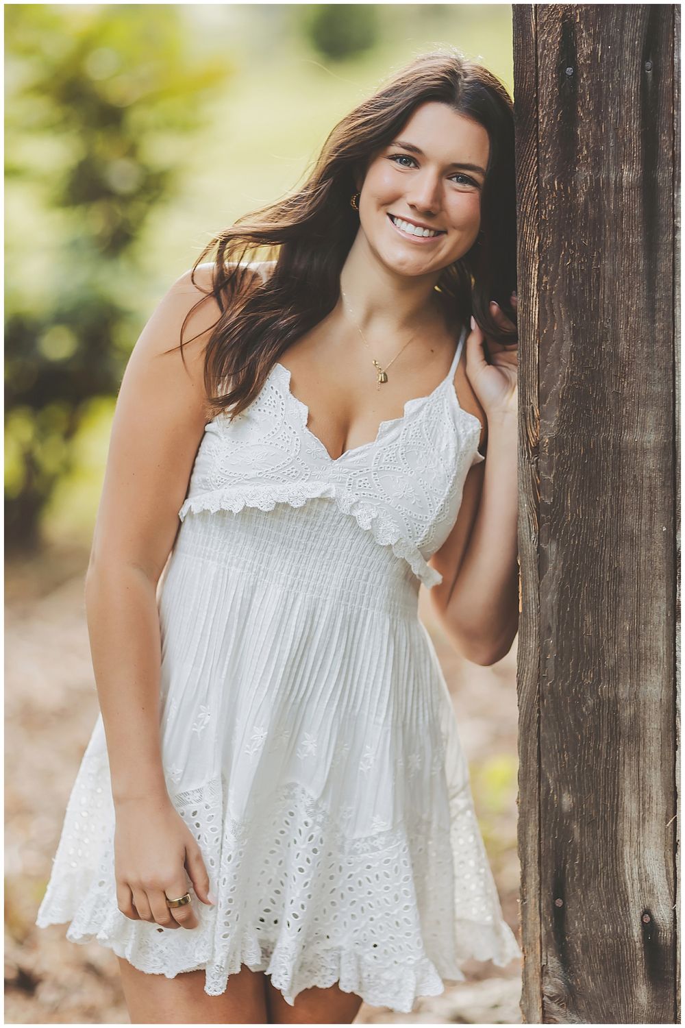 Portraits in white eyelet lace top with wooden fence backdrop.