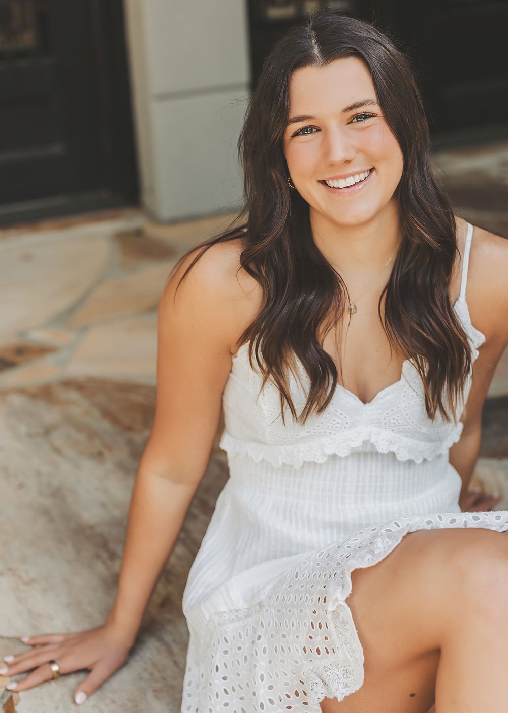 Casual portraits in white eyelet top on textured concrete background.