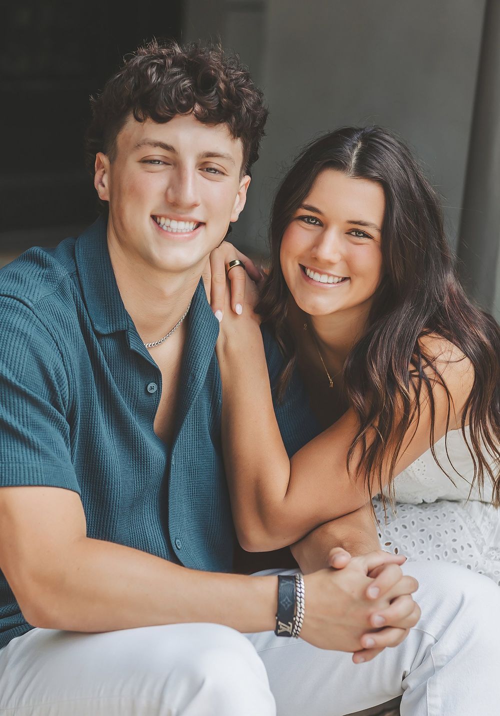 A happy young couple sitting close together and smiling warmly at the camera.
