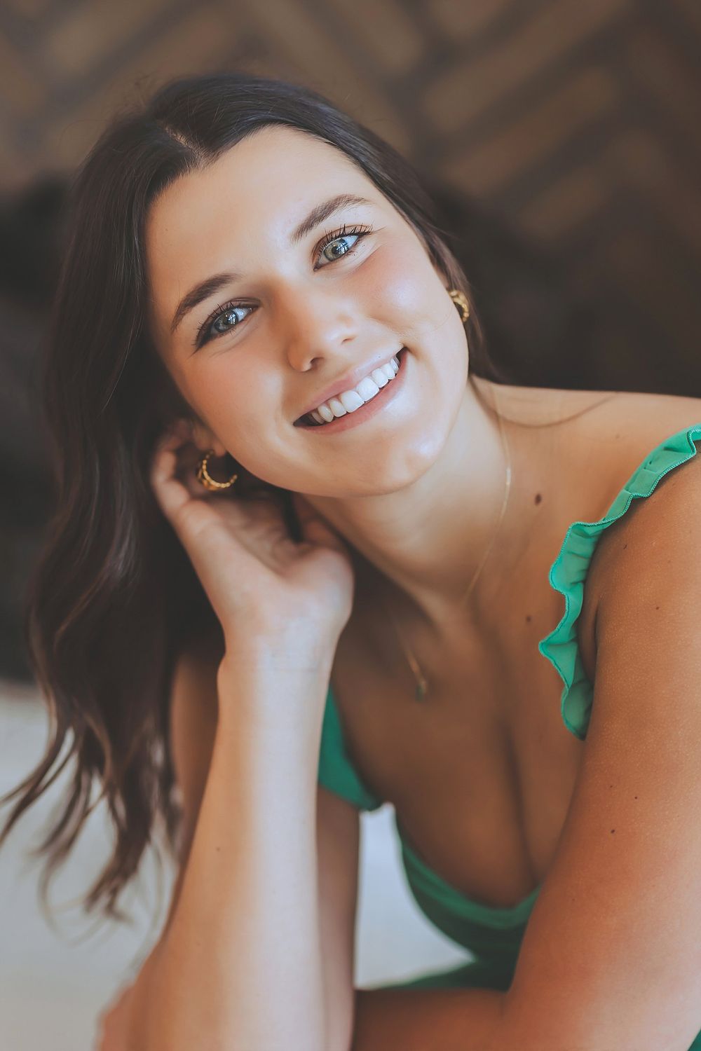 Portrait of a woman posing in green with natural lighting and a soft smile.