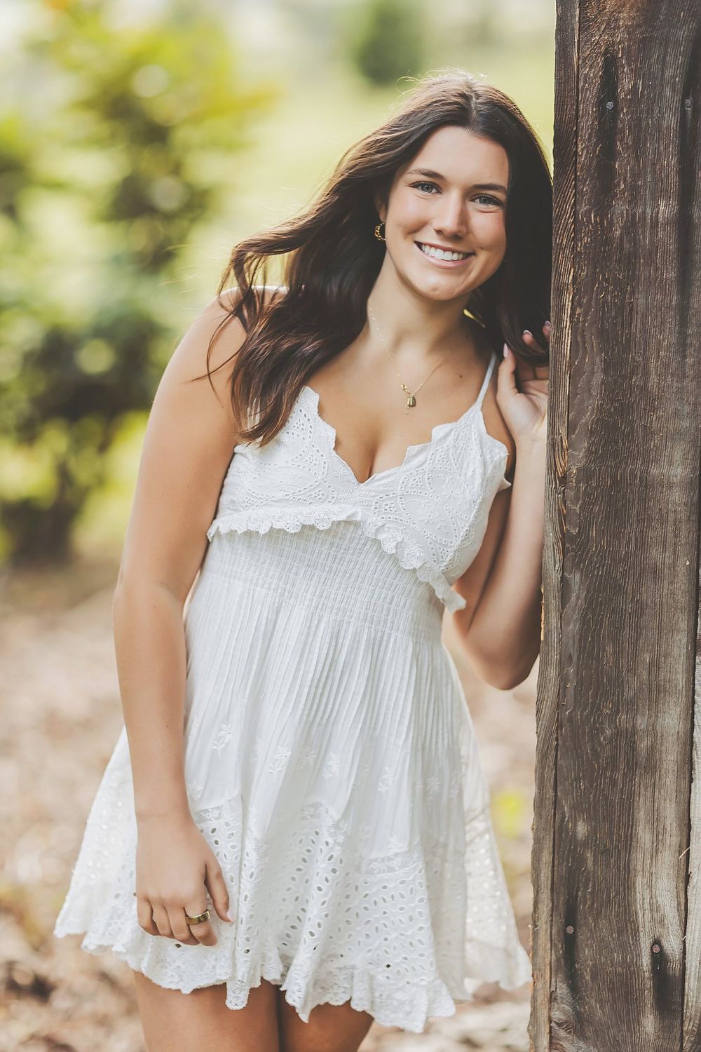 Outdoor portraits featuring a white eyelet dress and rustic wooden fence backdrop.