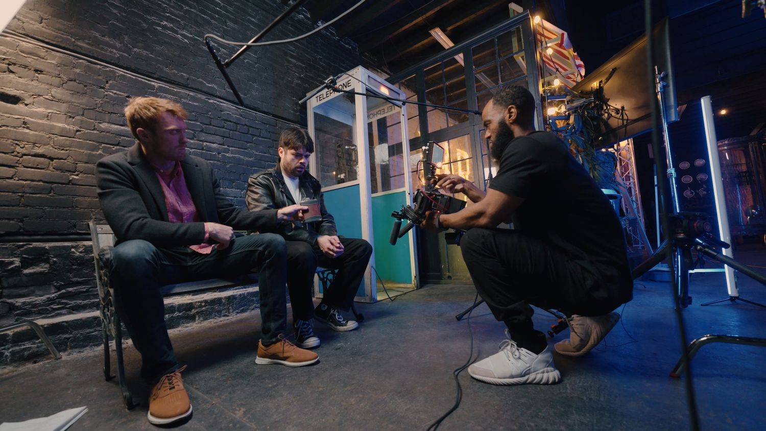 Group of people having casual conversation in dimly lit industrial space with blue lighting.