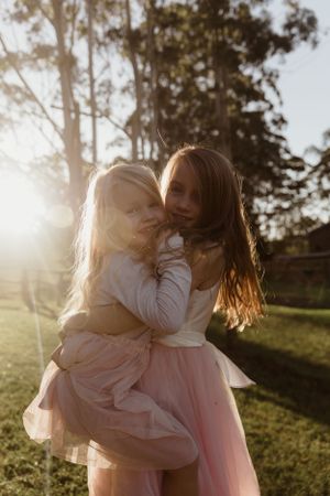 Parent and child sharing playful moment in golden afternoon light.