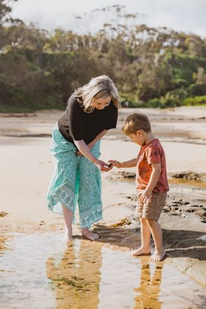 Two people exploring tide pools together on a scenic beach.