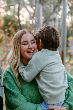 Tender moment captured between parent and child outdoors among autumn trees.
