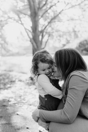 Black and white portrait of tender moment between parent and child outdoors.