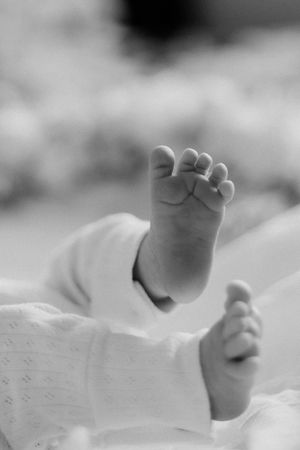 Black and white close-up of tiny baby feet against white fabric.