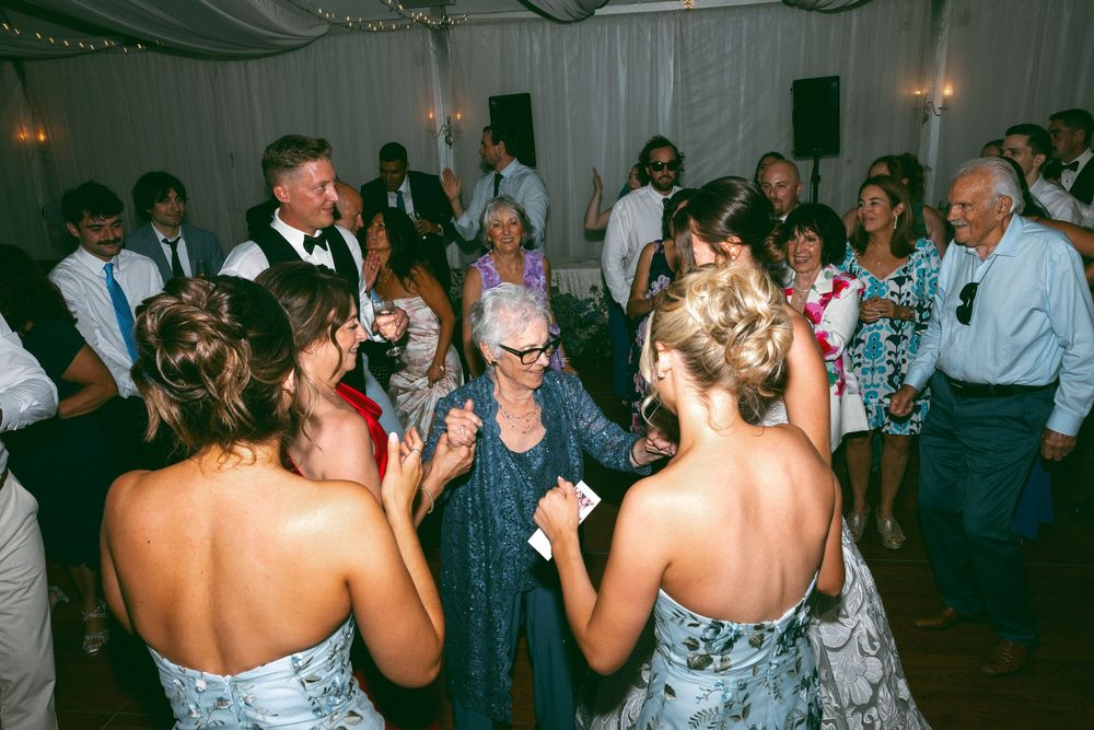 Wedding reception party with guests dancing under dimly lit tent.